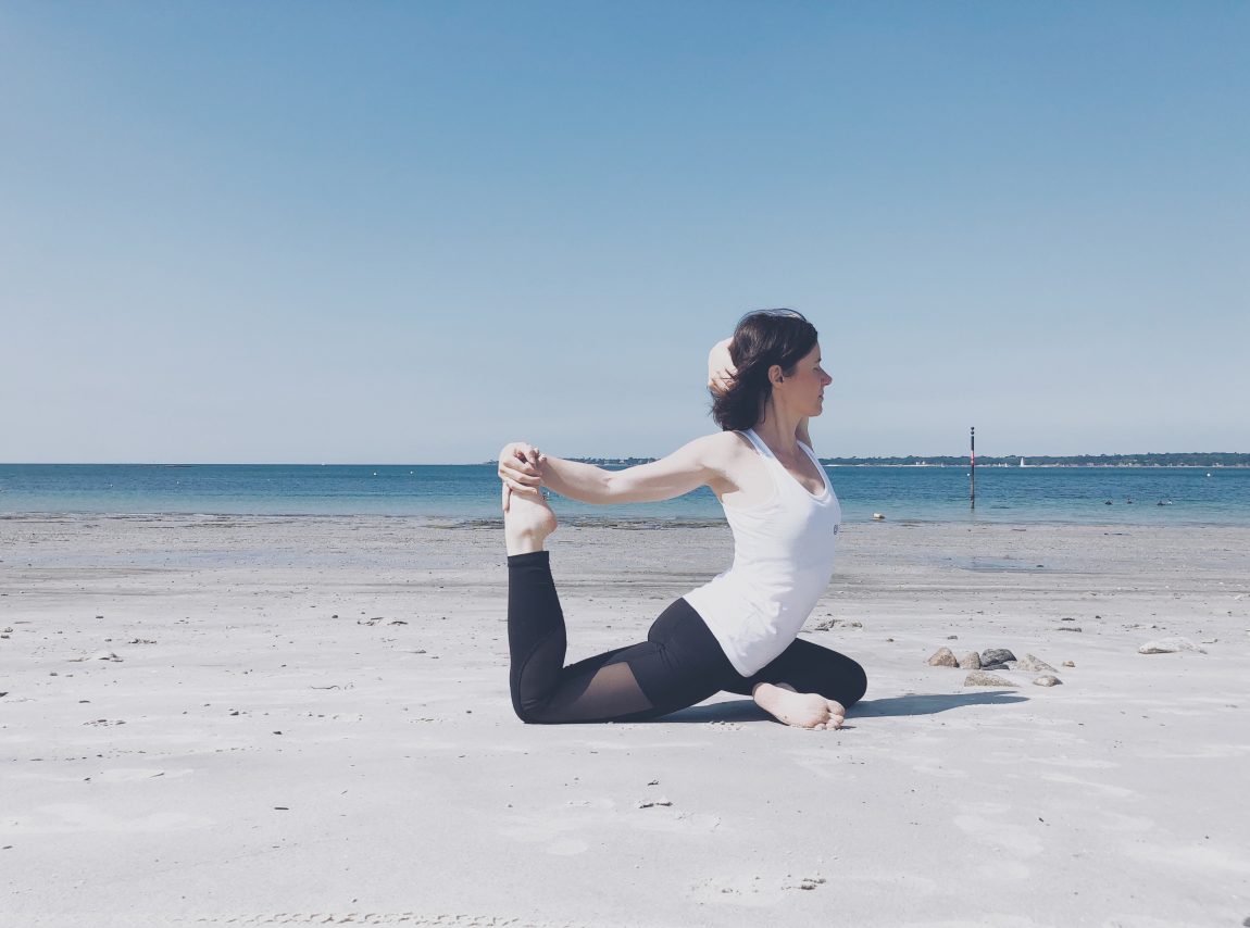 yogi girl femme yoga pose yoga plage mer océan bleu ciel sable legging yoga noir débardeur blanc yoga get yogi